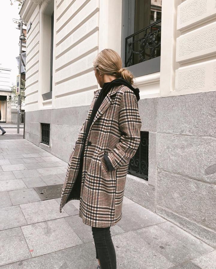 Claudia Parras acompañó una sudadera negra con un abrigo de cuadros de Clott.