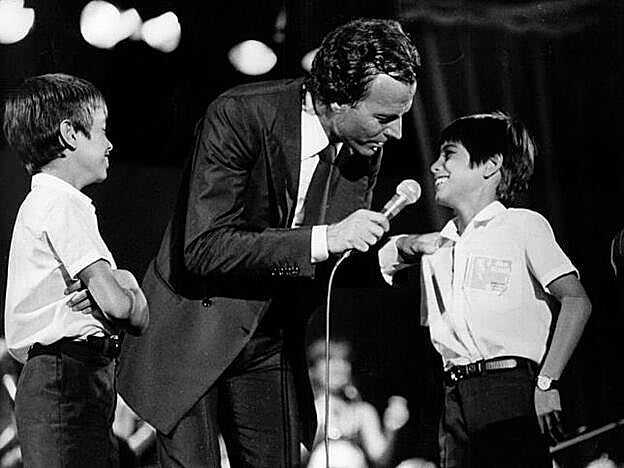 Julio Iglesias junto a sus hijos, Enrique y Julio José, sobre un escenario en una imagen de los años 80.