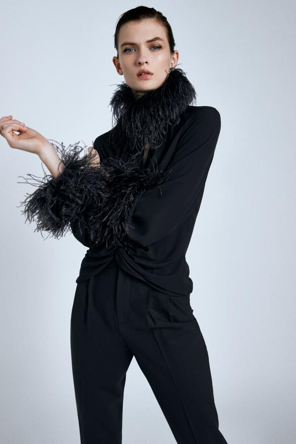 Si eres friolera pero no renuncias a un look nocturno lleno de estilo, en Zara puedes encontrar esta blusa de cuello subido con plumas y manga larga acabada en el mismo efecto. Tiene escote de pico y bajo acabado en nudo delantero y cuesta 69,95 euros. Solo queda en las tallas XS, S y M.