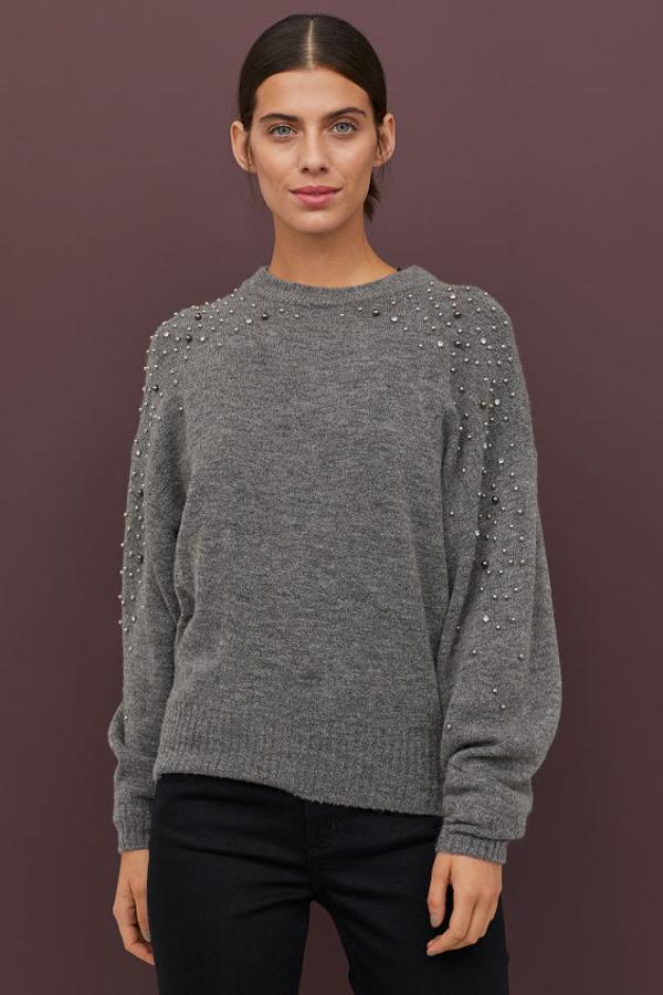 Con perlas en varios tonos repartidas por los hombros y el cuello, este jersey con cuello, puños y bajo en punto de canalé y color gris marengo es de H&M, cuesta 19,99 euros y quedan pocas existencias en todas las tallas.