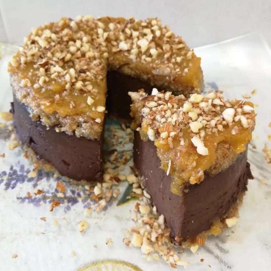 Ingredientes:-50 gr aceite de coco-120 gr avellana-60 gr dátil-300 gr calabaza-150 gr chocolate 90%-Almendra picada-1 caqui muy maduroPreparación:- Echamos el aceite de coco en un vaso y calentamos 1 minuto en el microondas. Lo trituramos junto con los dátiles y las avellanas.- Extendemos la mitad de esta mezcla en la base del molde de manera que quede compacta. (la otra mitad la dejaremos para la parte de encima).- Asamos o cocinamos al vapor la calabaza (yo la he cocinado el el Lekue 5 min. en el microondas). Añadimos el chocolate para que se funda con el calor de la calabaza y trituramos ambos ingredientes hasta que quede una mezcla homogénea.- Vertemos en el molde encima de la base. Refrigeramos un poco para que sea más fácil poner la otra mitad de la base encima.- Ponemos la otra mitad de la base. Luego habrá que volcar el molde así que no pasa nada si no queda perfecto porque se verá encima la otra parte.- Metemos en el frigorífico durante varias horas hasta que se enfríe. Luego lo desmoldamos en un plato.- Para hacer la mermelada de caqui tan solo hay que cortarlo y triturarlo con la batidora (más o menos en función de si se quiere con cachos de fruta o no). Luego se pone en una cazuela al fuego y se va moviendo hasta que coja la consistencia de mermelada.- Decoramos por encima con mermelada de caqui y espolvoreamos almendras picadas.