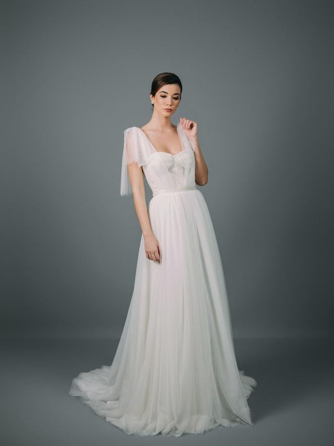 Vestido de novia con voluminosa falda de fino tul con cola. Corpiño entallado confeccionado con tejido de fantasía y detalle con tirantas de tul.