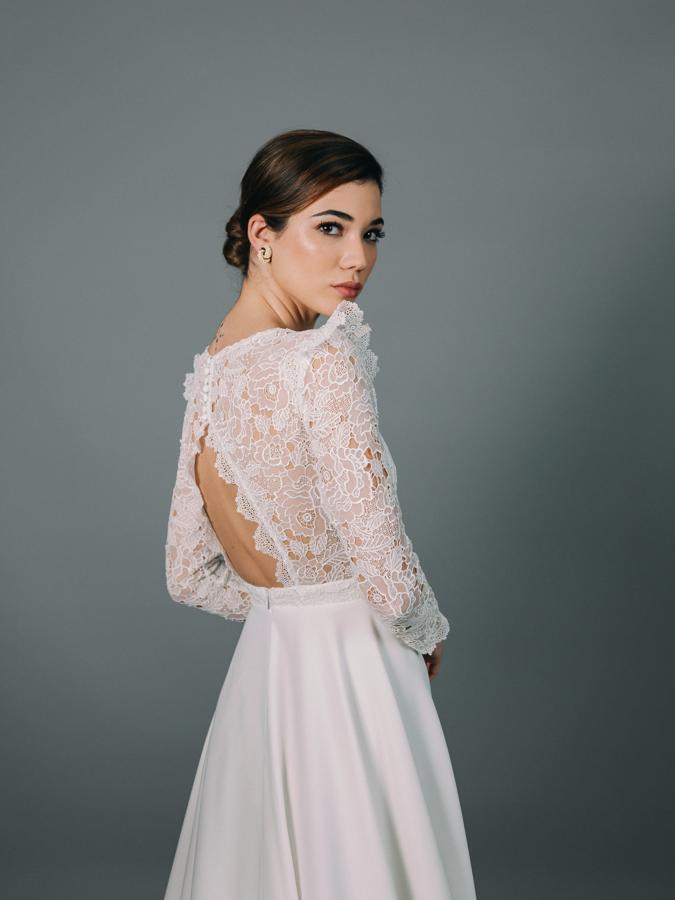 Vestido de novia con cuerpo entallado y manga francesa, confeccionado en fino guipur, corte en la cintura y falda con cola de crepé.