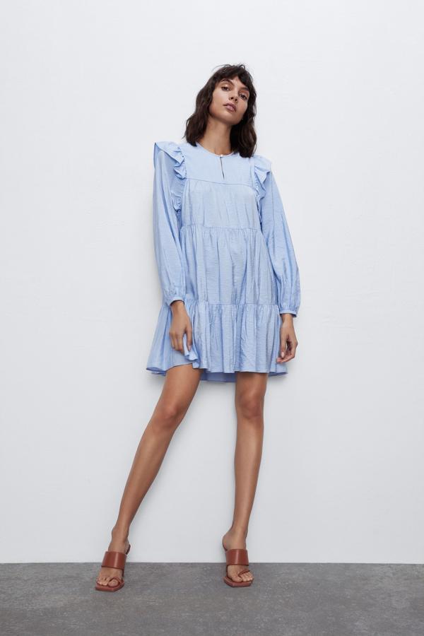 Vestido de cuello redondo y escote pico con botón joya. Manga larga acabada en puño. Detalle de volantes.