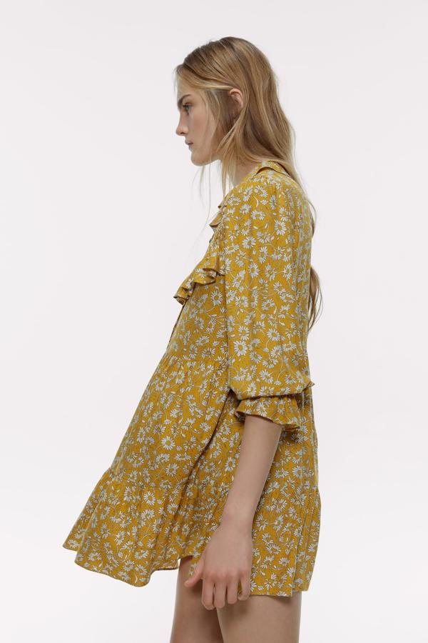 Vestido con cuello redondo y manga larga. Detalle de elástico delantero tipo nido de abeja y aplicación de volantes. Cierre frontal con botones.