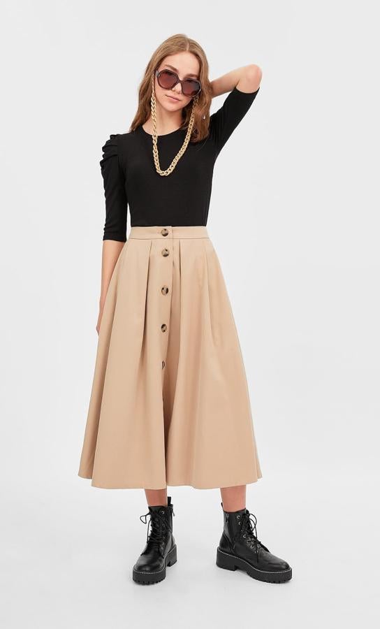 Sin tablas pero con vuelo, esta original propuesta de Stradivarius en color camel con botones grandes en el frontal cuesta 25,99 euros y está disponible entre las tallas 34 y 40. Imprescindible para las fans del negro, porque ya sabemos lo bien que funcionan estas combinaciones.