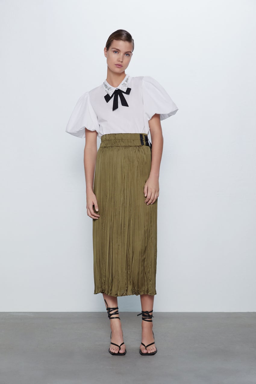 Falda midi satinada efecto arrugado en tono khaki de Zara con hebillas ajustables en la cintura. (25,95 euros).