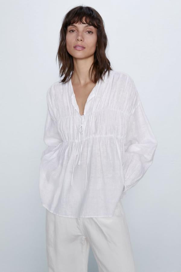 Cuello redondo y manga larga acabada en elástico para esta blusa con detalle de frunces en el delantero y cierre frontal con lazos. Es de Zara, cuesta 29,95 euros y está disponible entre las tallas XS y XXL.