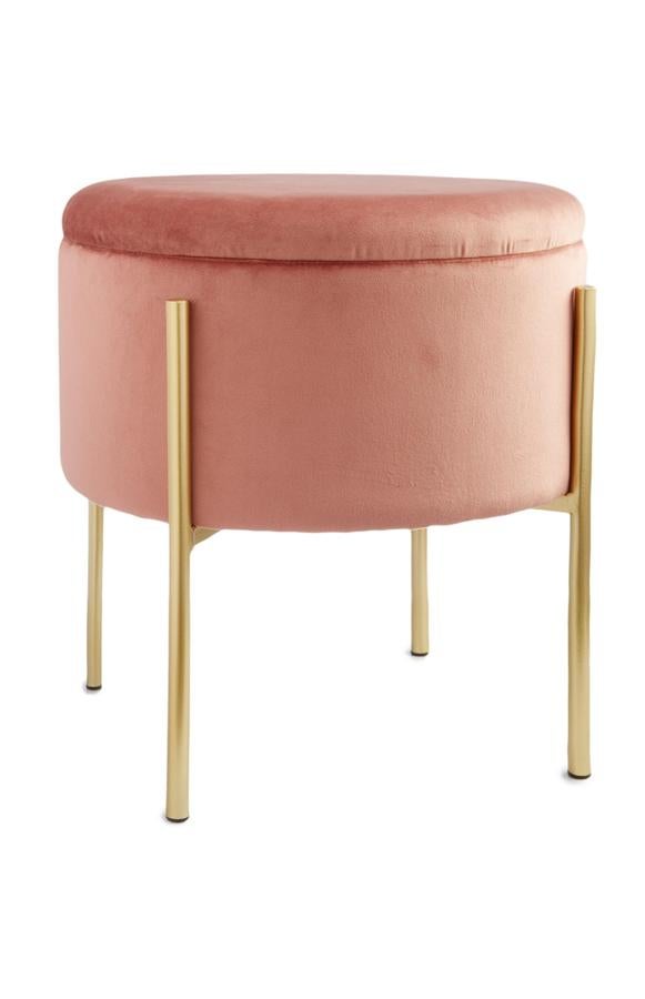 Este taburete de terciopelo rosa y patas doradas te quedará genial tanto en el salón como en tu dormitorio. La parte superior es una tapa, y dentro podrás almacenar. Cuesta 26 euros.