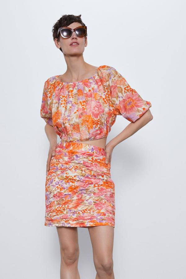 De cuello redondo y manga por debajo del codo, esta blusa de tejido drapeado y estampado floral está disponible desde la talla XS a la L. Con elástico en el bajo y en la manga, tiene un precio de 25,95 euros, y la puedes combinar con falta a juego.