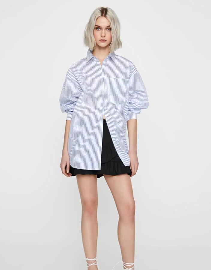Camisa de corte oversize en color blanco con rayas azules de manga larga. Es de Pull & Bear, confeccionada en algodón y disponible en las tallas S, M y L. Su precio es de 22,99 euros.