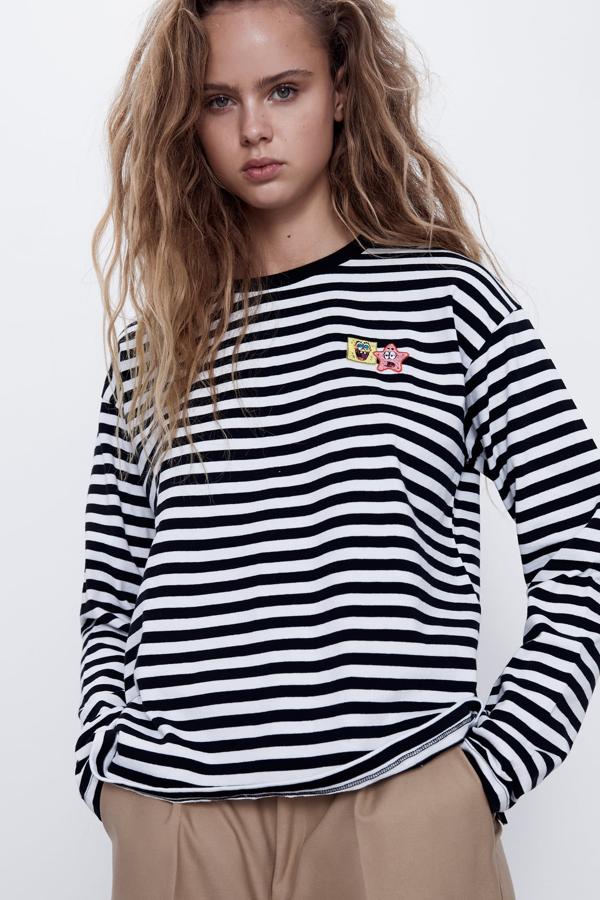 De manga larga, a esta camiseta con un 50% de algodón orgánico le han salido muchos pretendientes. Es de Zara y destaca el bordado con los personajes de la serie 'Bob Esponja'. Disponible en las tallas S, M y L, tiene un precio de 17,95 euros.
