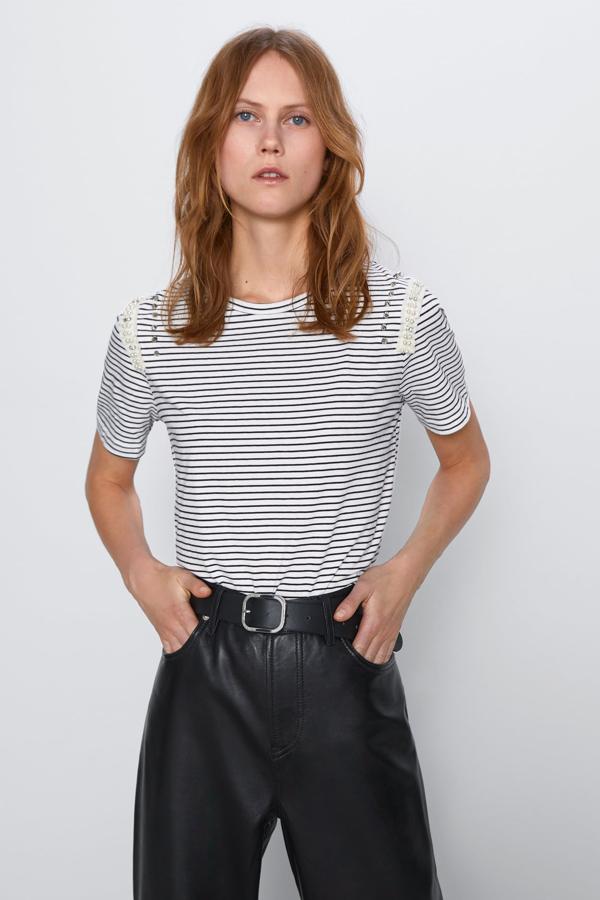 Con rayas finas, esta camiseta de manga corta de Zara cuenta con aplicaciones de tachas y abalorios en la zona de los hombros. Disponible de la talla S a la XL y tiene un precio de 15,95 euros.