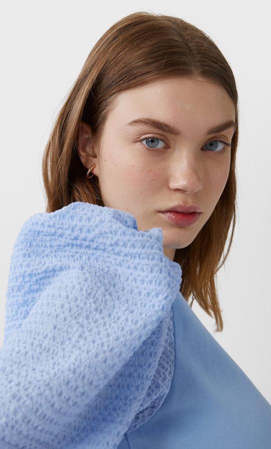 La manga abullonada va a seguir con nosotras durante todo el verano y esta camiseta es buena prueba de ello. En azul cielo, confeccionada en dos texturas, ha pasado de 12,99 euros a 6,49 euros. Solo queda en la talla S, talla en la que también está disponible en color negro.