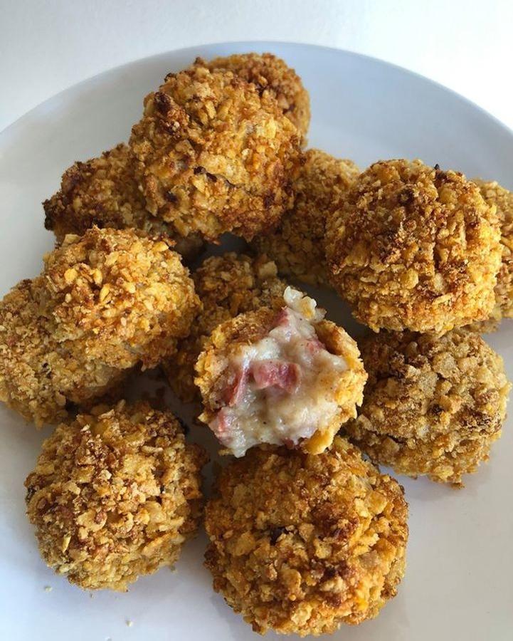 Ingredientes para la bechamel:CebollaAOVETaquitos de jamónHarina integral de espeltaLechePimienta negraIngredientes para el rebozado:1 huevoCopos de maíz sin azúcarPreparación:- En una olla, echamos el AOVE y sofreímos la cebolla y los taquitos de jamón. Añadimos la harina de espelta hasta que se haga. No debe quedar cruda.- Vamos añadiendo leche hasta formar una masa consistente y que se despegue con facilidad.- Dejamos enfriar y reposar la masa 24 horas.- Trituramos los copos de maíz.- Hacemos las bolitas col ma masa y pasamos una a una por el huevo y después por los copos de maíz.- Metemos al horno hasta que se doren por fuera.