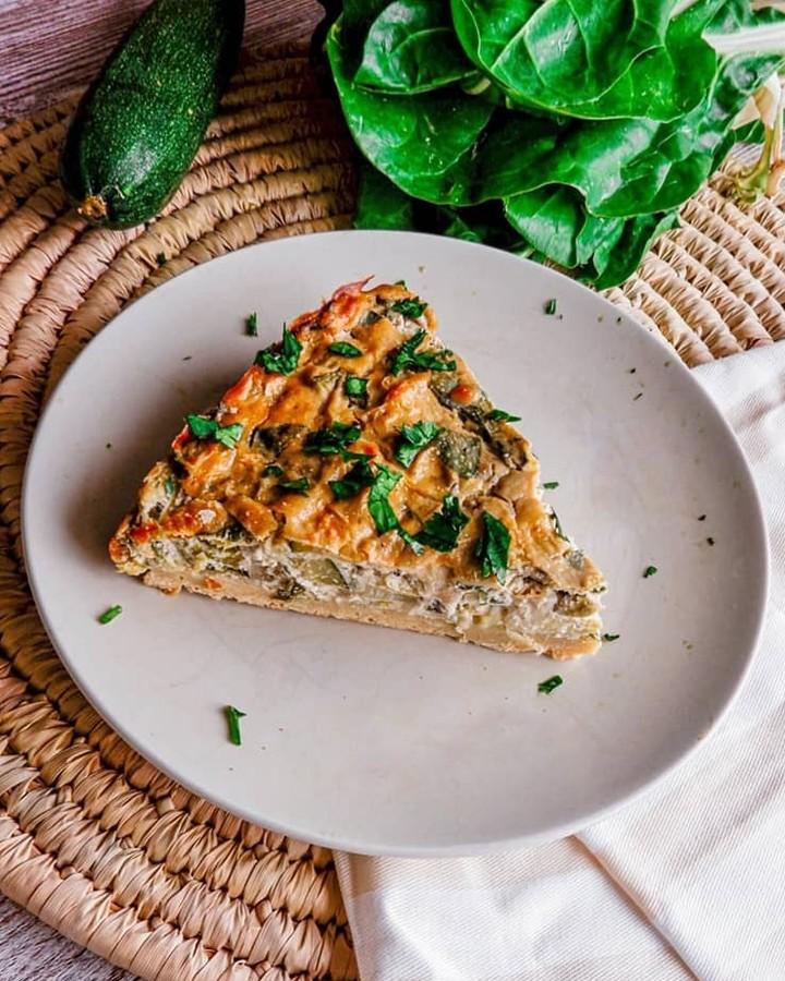 Ingredientes:1 taza de harina de garbanzo1/2 taza de otra harina sin gluten1 cg semillas de lino molido1 taza de aguaUna pizca de salAjo seco1 puerro1 puñado de acelgas1 calabacín pequeño5 champiñones1 bloque de tofu firme1/2 taza de leche vegetal1/2 taza de anacardos remojadosUna pizca de sal negraLevadura nutricionalAjo en polvoCebolla en polvoPimienta Preparación:- Mezclamos las harinas y las semillas de lino y vamos añadiendo agua poco a poco hasta que quede una masa que se pueda untar. Lo dejamos reposar un rato.- En un molde y con papel de horno, esparcimos la base de forma que no quede muy gruesa y horneamos a 180ºC durante 20 minutos.- Salteamos las verduras con una pizca de sal y pimienta. Reservamos.-Vertemos las verduras y el resto de ingredientes en la base y horneamos a 180ºC durante 30 minutos.