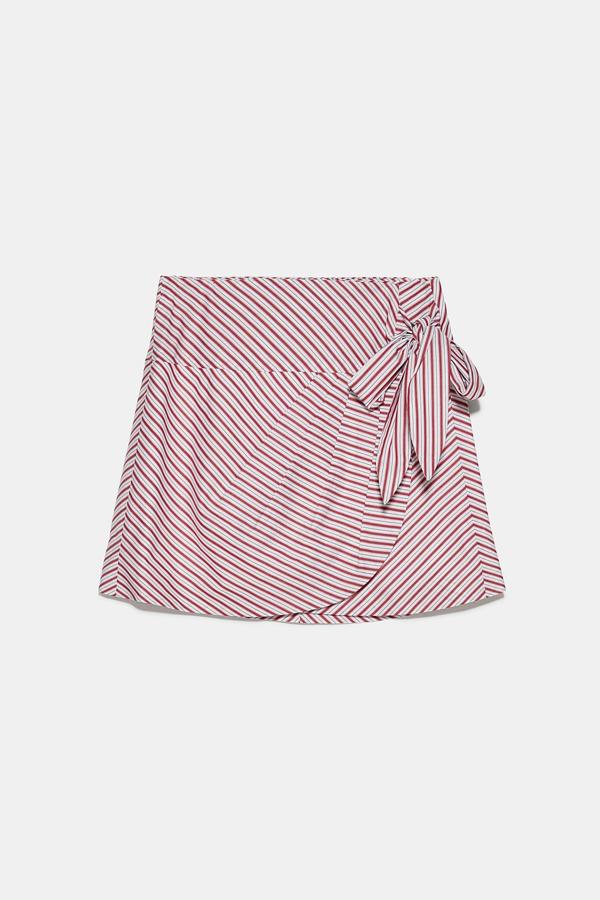 Muchos admiradores le están saliendo a esta minifalda tipo pareo de tiro alto con detalle de pliegues en la parte delantera. Se cierra con botones interiores y tiene una lazada lateral. Es de Zara, y tiene un precio de 25,95 euros.