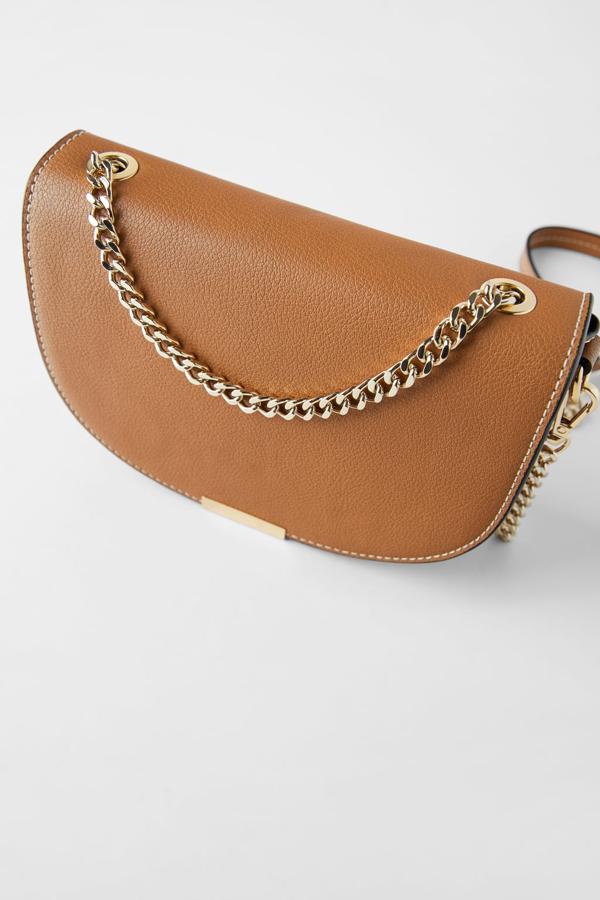 Disponible en marrón y burdeos, esta bandolera ovalada de Zara viene con detalle de pieza metálica en la solapa y asa de hombro extraíble con cadena en combinación de materiales. De 19,95 euros ha pasado a 9,99 euros.