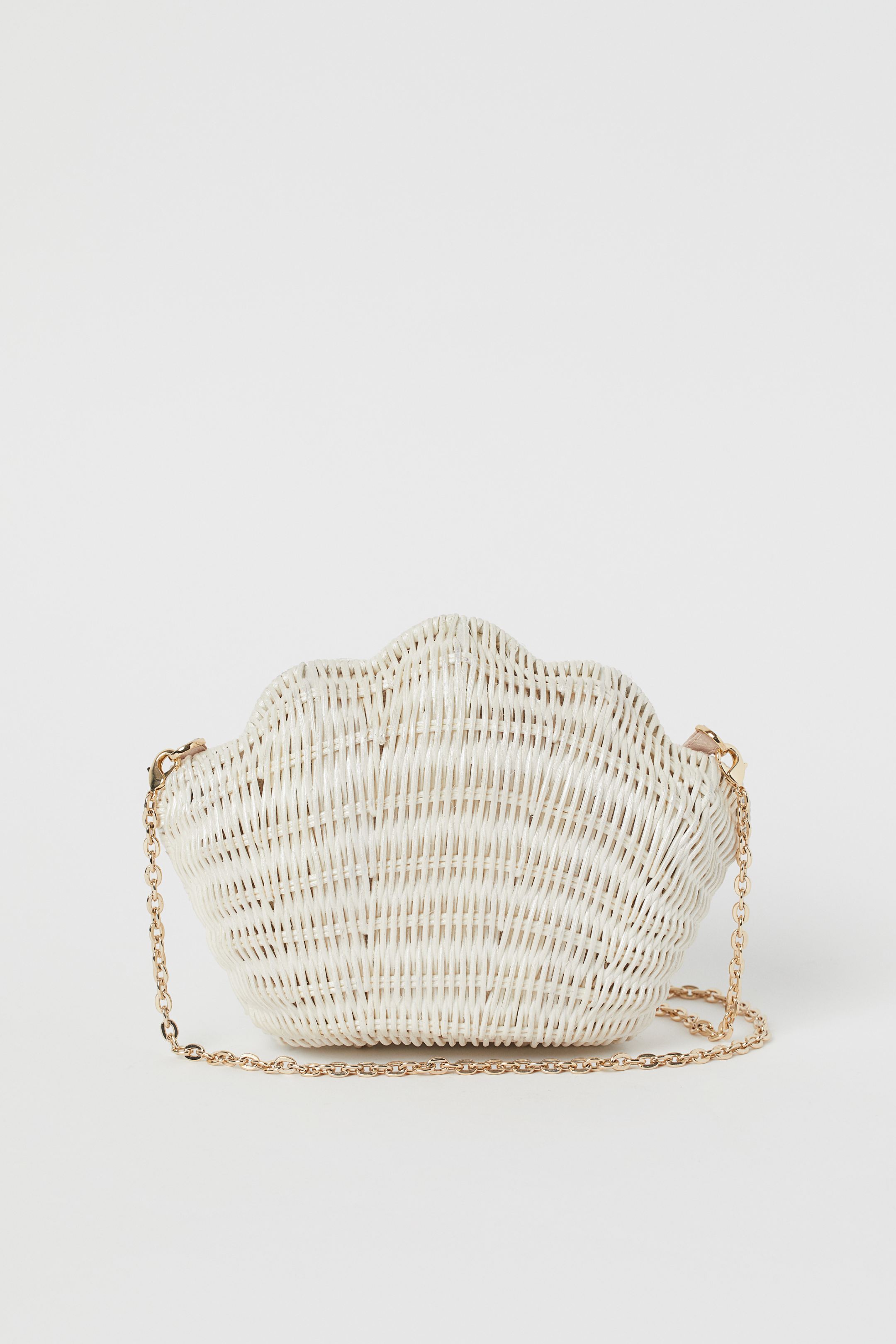 La nueva colección de H&M tiene accesorios tan caprichosos como este clutch de ratán blanco en forma de concha. (34,99 euros).