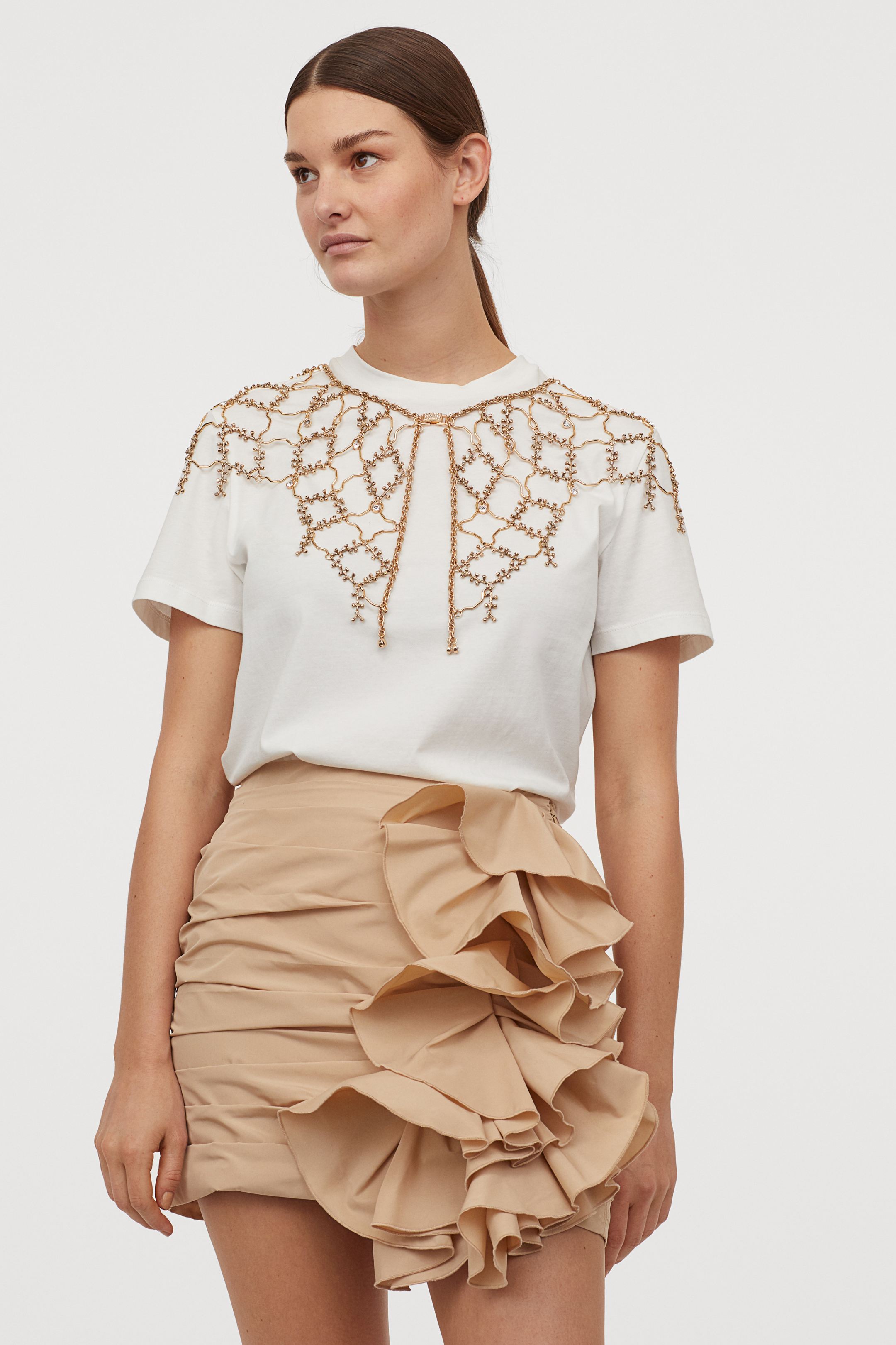 De nuevo los volantes y el efecto drapeado triunfan en esta minifalda de H&M en tono beige con el que podrás crear un efecto nude y así alargar tus piernas hasta el infinito. (49,99 euros).