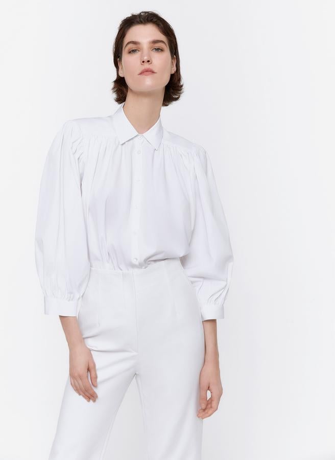 Nunca le falta en su fondo de armario una buena camisa blanca. Pero seguro que no tiene ninguna como esta, con mangas abullonadas y hombreras. Es de la colección P/V de Uterqüe.