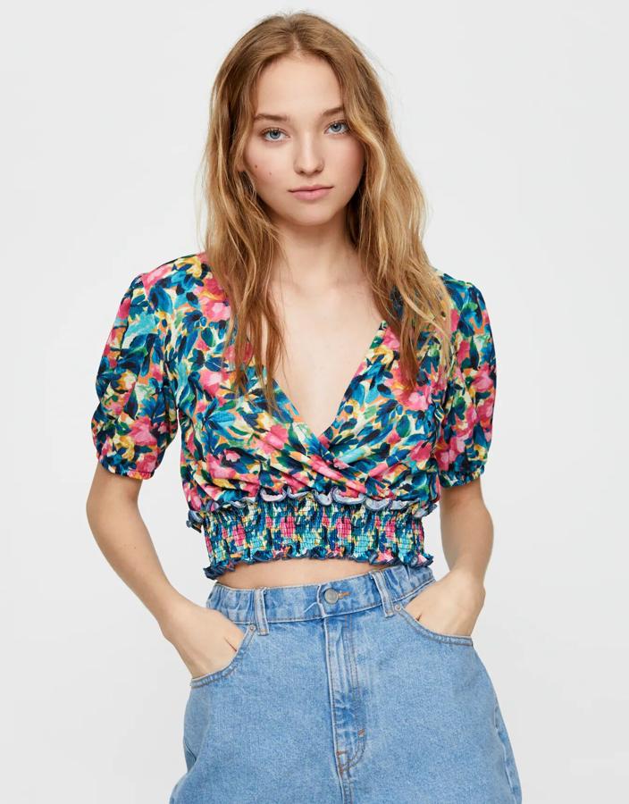 Esta floreada camiseta con detalle de goma en la cintura y escote de pico cuenta con tejido elástico y te combinará genial con todo. Tiene un precio de 15,99 euros.