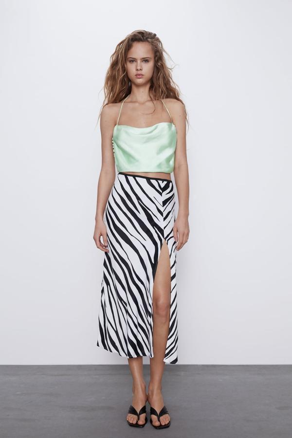 Una de nuestras propuestas favoritas es esta falda midi de tiro alto con cintura elástica y bajo con abertura frontal de Zara. Con estampado de cebra, costaba 25,95 euros y ahora podemos comprarla por 12,99 euros. Está disponible entre las tallas XS y XL.