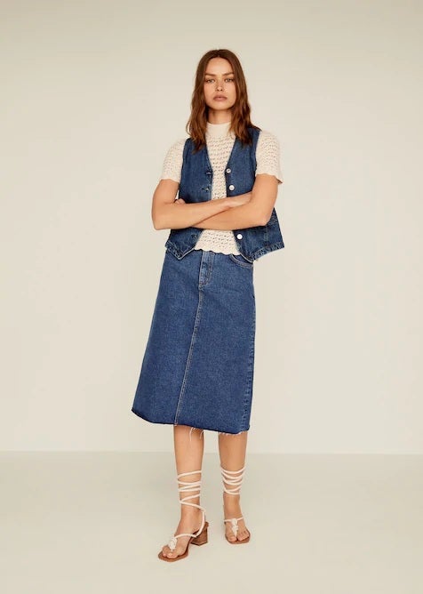 Falda vaquera de corte midi con bajo deshilachado de Mango. (29,99 euros).