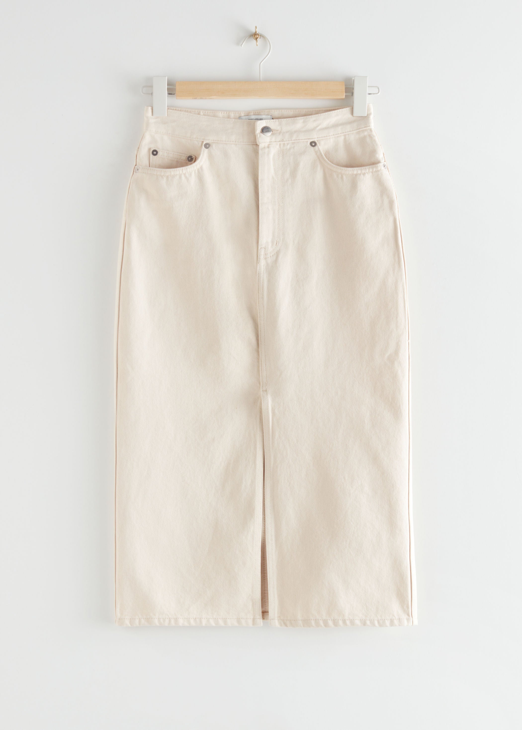 Falda midi vaquera en tono crema con abertura delantera y diseño lápiz de &Other Stories. (69 euros).