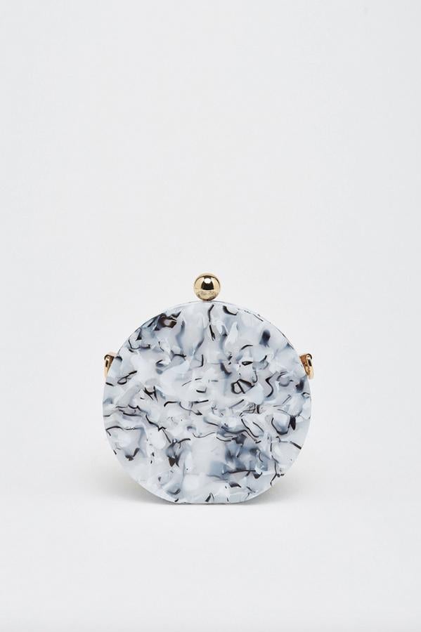 Diseño redondo en efecto mármol para este bolso de mano de Sfera en tonos blancos y negros con cierre tipo bola en color dorado, el mismo color del asa de hombro. Costaba 17,99 euros y ahora tiene un precio de 10,75 euros.