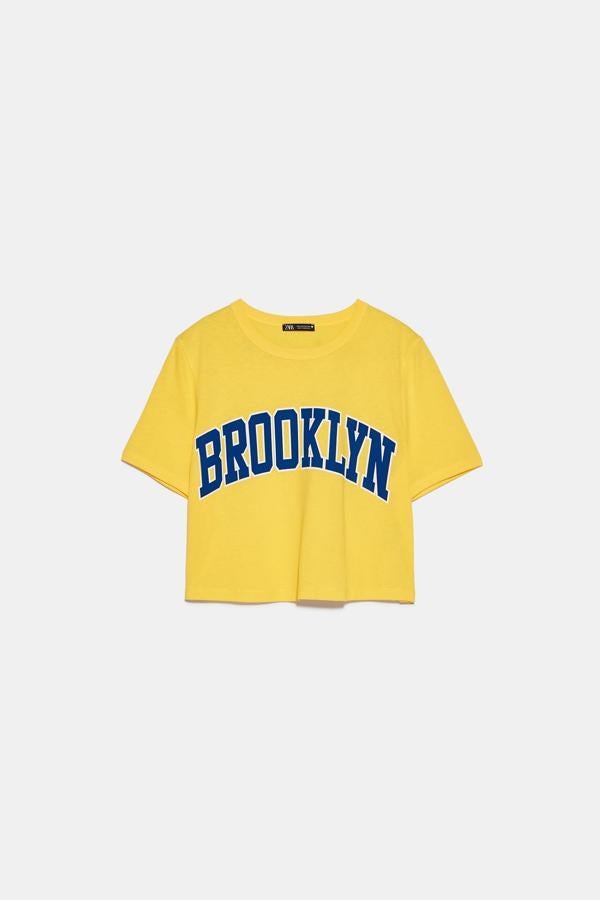 Otra propuesta muy cosmopolita de Zara es esta camiseta amarilla con Brooklyn en letras azules. Con cuello redondo y manga corta, cuesta 5,95 euros y está disponible en las tallas S, M y L.