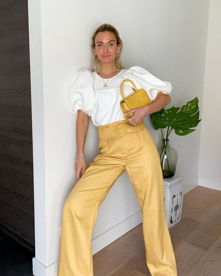 Pantalones de color con blusa blanca de mangas abullonadas.