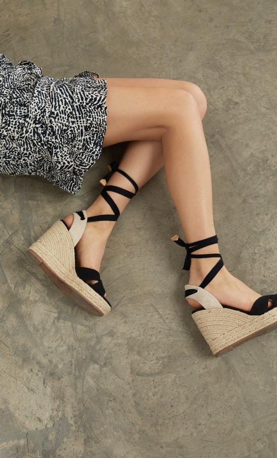 Sandalias negras con cuñas de esparto y cintas para atar alrededor del tobillo, de Stradivarius (29,99 euros).