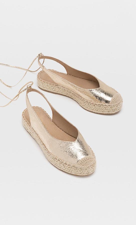 En color dorado, y también disponibles en marrón, estas esparteñas destalonadas con cinta atada al tobillo tienen un precio de 25,99 euros.