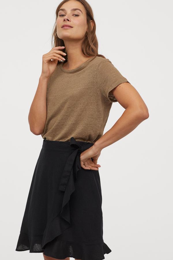 Esta falda cruzada de lino en color negro con ribete de volante es de talle alto y te resultará de lo más cómoda y versátil. Tiene un precio de 24,99 euros.