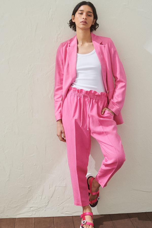 Este traje de lino en color rosa está formado por una americana (29,99 euros) con bolsillos delanteros y botón, y pantalón (19,99 euros) con cinta ajustable a la cintura.