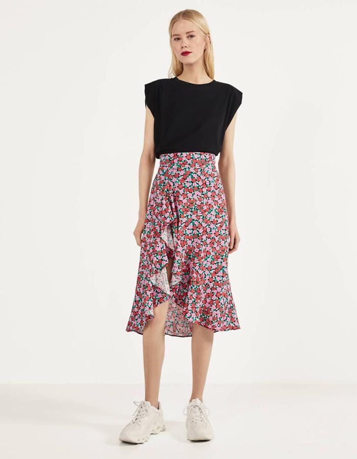 Estampado de flores rosas y rojas para esta falda de Bershka con abertura lateral acabada en volantes. Tiene un precio de 22,99 euros y está disponible entre las tallas XS y L.