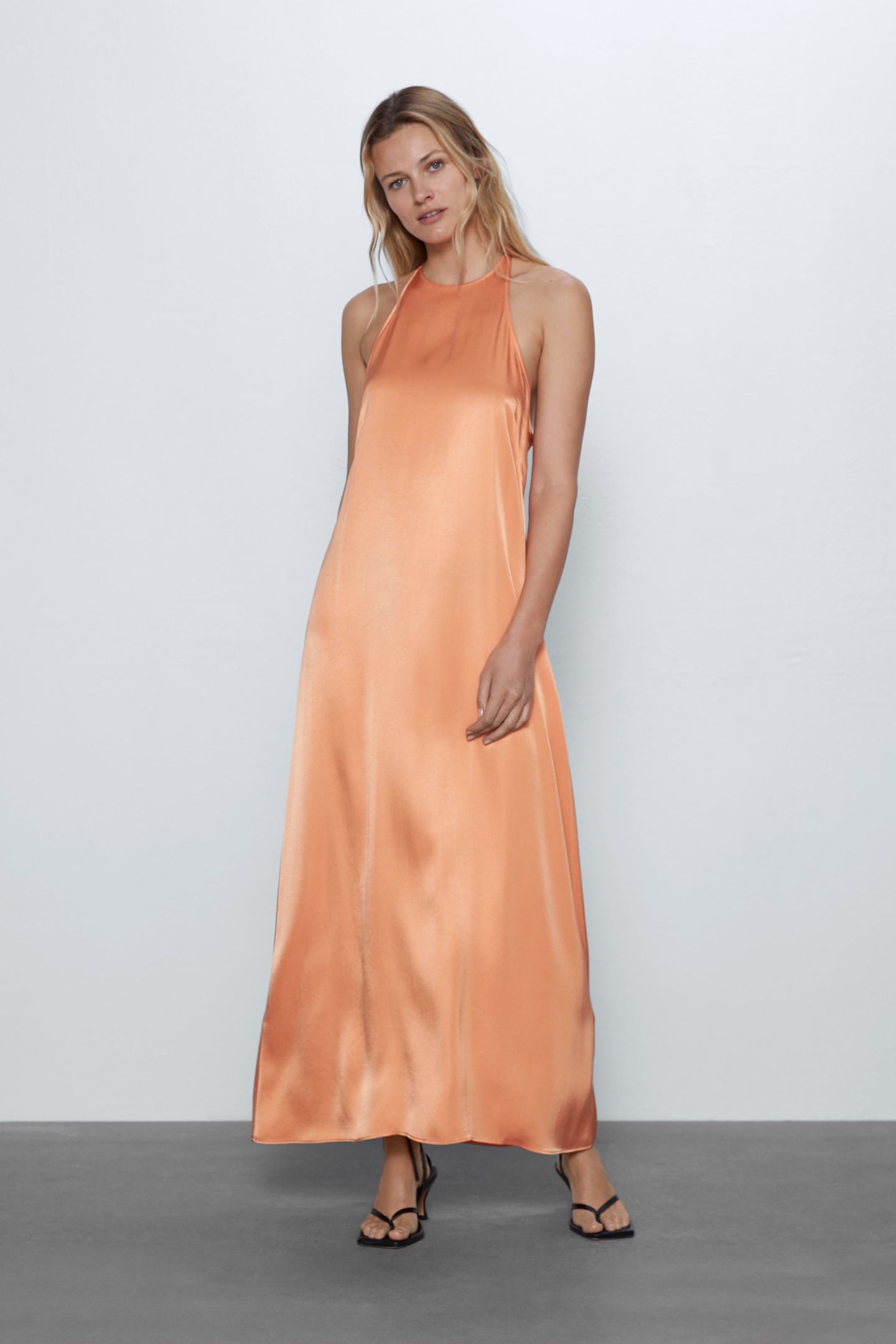Tendencia por partida doble en este vestido de Zara. ¿Las encuentras? El tono mandarina pastel de acabado satinado que iluminará tu bronceado este verano y el cuello halter que estiliza a tope los hombros. (15,99 euros).