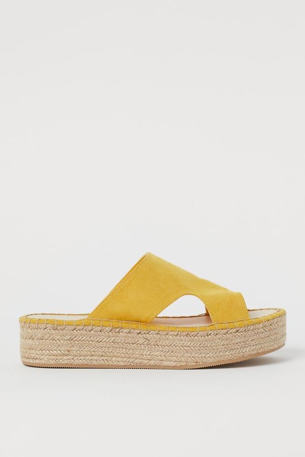 Estas sandalias de ante sintético con plataforma en yute trenzado están confeccionadas con materiales parcialmente reciclados. En color amarillo, tienen un precio de 24,99 euros.