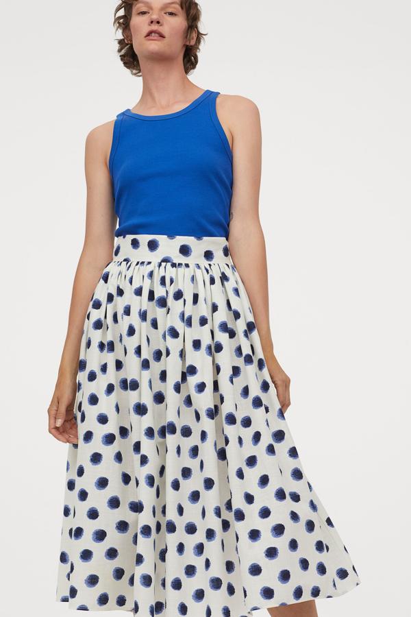 Esta falda midi en algodón vaporoso te dará mucho juego esta temporada. Con fondo blanco y lunares azules, es de talle alto y tiene un precio de 39,99 euros.
