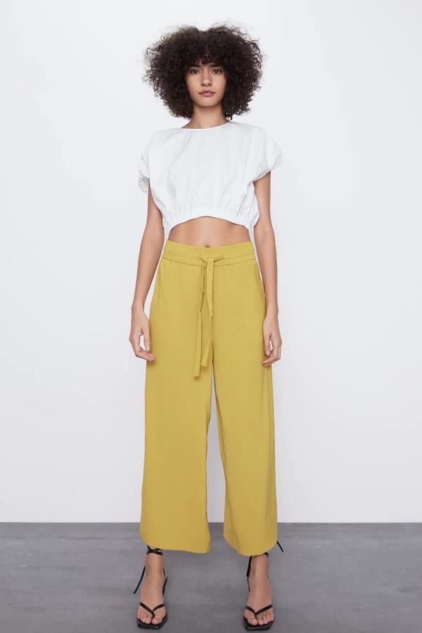 En color amarillo dorado, este pantalón fluido de tiro alto con cintura elástica ajustable con lazada del mismo tejido, cuenta con bolsillos laterales y tiene un precio de 19,95 euros. Es de Zara.