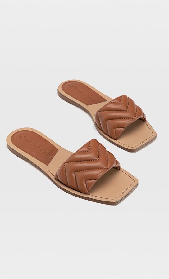 En color cuero, estas cómodas sandalias planas de Stradivarius cuentan con tira ancha acolchada y tienen un precio de 19,99 euros.