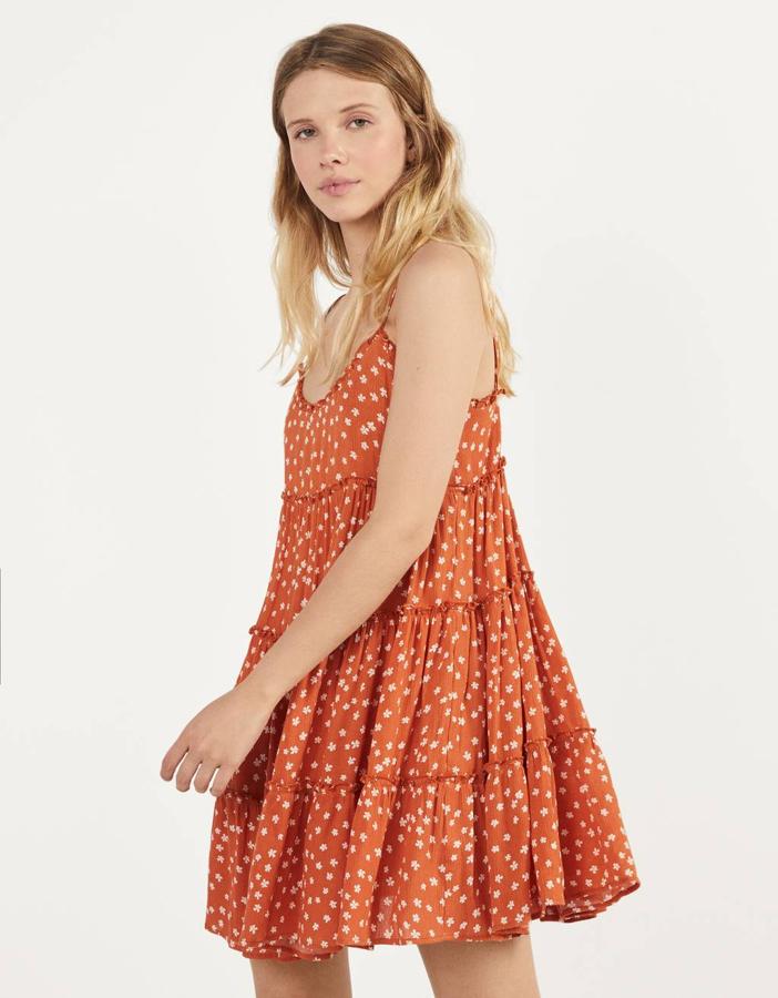 En color camel, con flores en color blanco, este vestido de Bershka viene con una bonita sucesión de volantes y tirantes finos. Tiene un precio de 19,99 euros y está disponible entre las tallas XS y L.