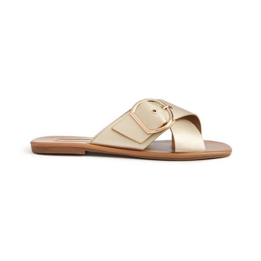 Sandalias tipo mule en color dorado con adorno de hebilla (8 euros).
