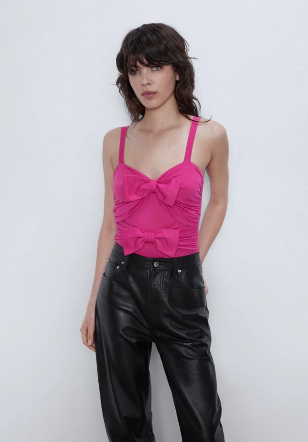 Body fucsia de escote pico y tirantes, con dos lazos en delantero. Cierre en bajo con botones a presión (Zara, 15,95 euros).