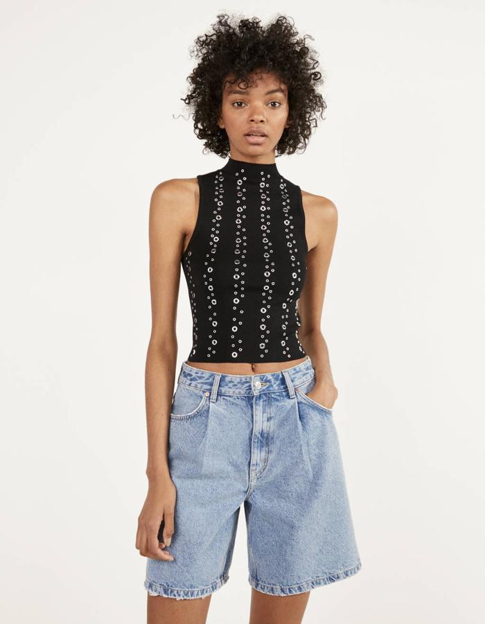 En negro, con cuello halter y sin mangas, este top cubierto de tachuelas tiene  un precio de 15,99 euros  y está disponible entre las tallas XS y L.