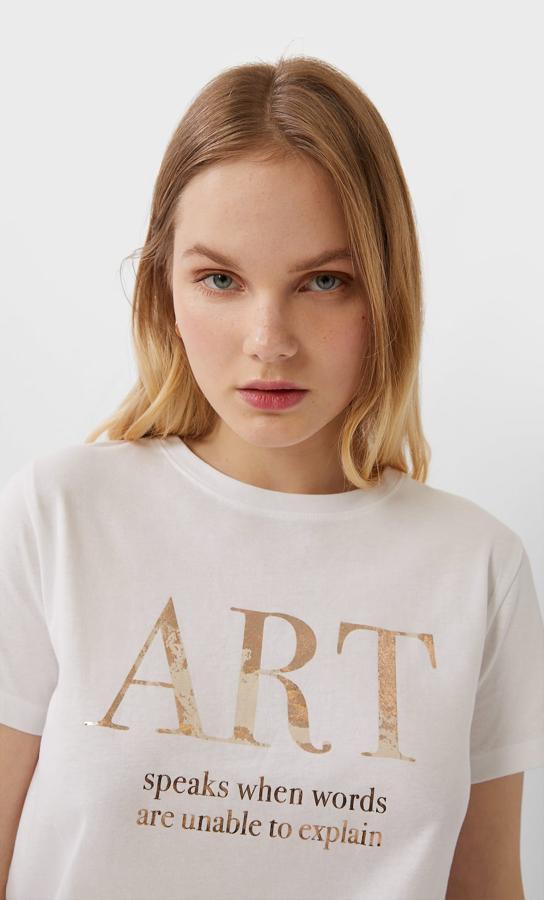 “El arte habla cuando las palabras no pueden explicarlo” es el mensaje en tonos dorados de esta camiseta blanca de Stradivarius que cuesta 7,99 euros y solo queda en la talla XL.