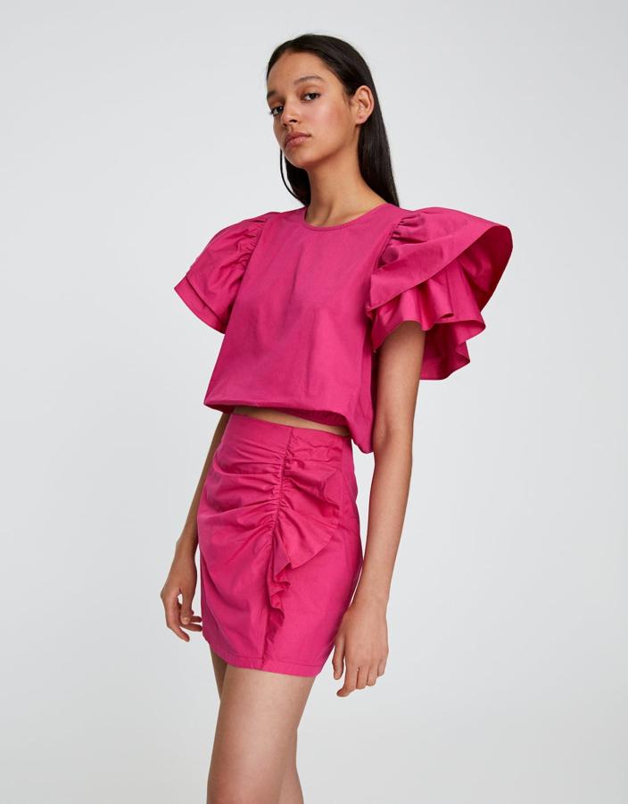 En color fucsia, esta minifalda con detalle de frunces y volante lateral tiene un precio de 9,99 euros. También puedes encontrar la blusa a juego con un precio de 9,99 euros.