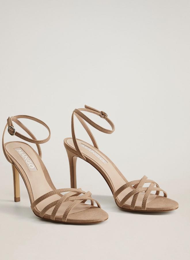 En color marrón, estas sandalias de tiras con punta redonda y tacón de 8 centímetros cuentan con costuras decorativas y pulsera en el tobillo. Son de Mango, y están rebajadas a 19,99 euros.