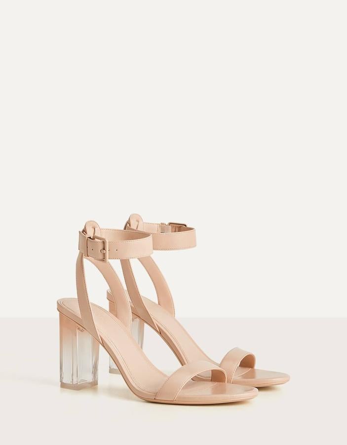 En color beige o negro, esta sandalia de tacón de metacrilato con tira en la parte delantera y cierre con hebilla al tobillo es de Bershka y tiene un precio de 22,99 euros.